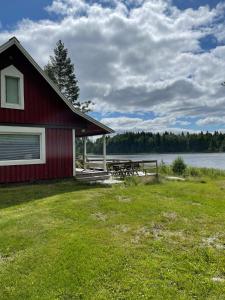 a red building with a picnic table next to a lake at Revontulet ZH Tuliaalto Moki in Pieksämäki