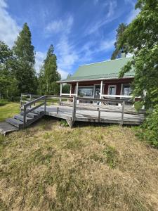 a home with a large wooden deck in the grass at Revontulet ZH Tuliaalto Moki in Pieksämäki