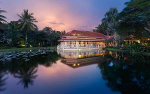 a building on a pond with lilies in the water at Sofitel Angkor Phokeethra Golf & Spa Resort in Siem Reap
