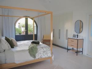 ein Schlafzimmer mit Himmelbett und Kommode mit Spiegel in der Unterkunft Lemon Tree Studio in Beechworth
