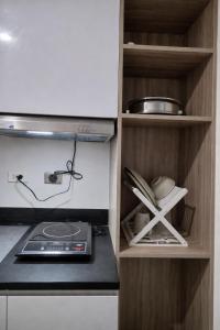 a kitchen with a stove and a shelf with dishes at Jtower residences mandaue 12th flr in Mandaue City