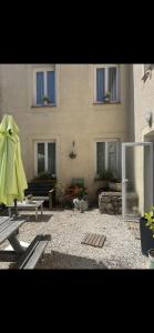 a building with a patio with a table and a green umbrella at Chambre la paix lot in Payrac
