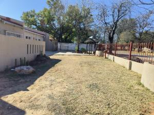 a fence and a dirt road next to a building at Ave Maria Camping site in Welkom +28 photos