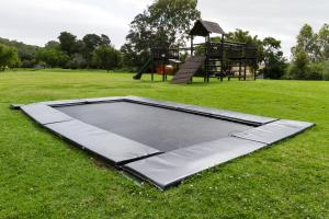 ein leeres Trampolin auf einem Feld mit Spielplatz in der Unterkunft Stonehill River Lodge by Dream Resorts in Buffeljagsrivier