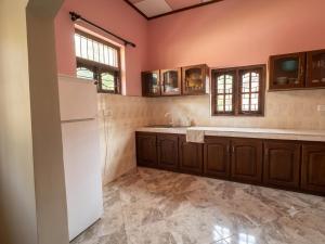 a kitchen with brown cabinets and a white refrigerator at DIMORA Bologngna in Chilaw