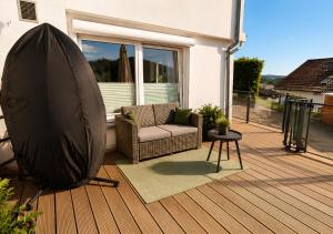 a patio with a couch and a table on a deck at Appartement - Eifelglück in Pelm +4 photos