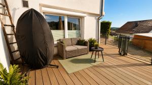 a wooden deck with a chair and an umbrella at Appartement - Eifelglück in Pelm
