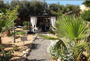 a pavilion in a garden with palm trees and bushes at TigerLounge in Douaïra