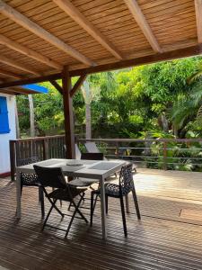 a table and chairs on a wooden deck at MANGOBELO entre océan et rivières in Capesterre-Belle-Eau