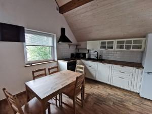 a kitchen with white cabinets and a wooden table at Domki Jaśmin 781-012-181 in Polańczyk