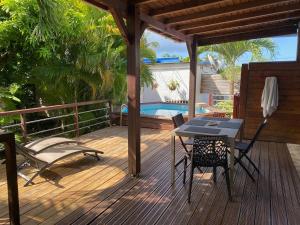 a deck with a table and chairs and a pool at MANGOBELO entre océan et rivières in Capesterre-Belle-Eau