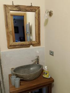 a bathroom with a stone sink and a mirror at La Sosto de Cesi - B&B in Grange Pieccia