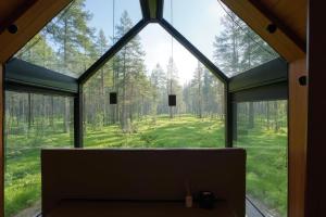a glass house in the woods with a large window at Sāmeland Retreat, Mirrored Glass Cabins, Swedish Lapland in Arvidsjaur