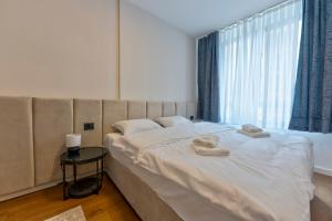 a bedroom with a large bed with two towels on it at Apartmani Aurora Zlatibor in Zlatibor +71 photos