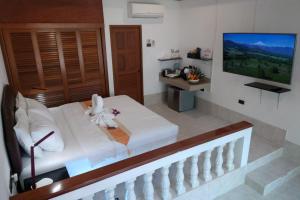 a bedroom with a white bed and a television at Samui Little Garden Resort in Chaweng