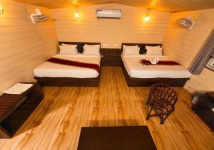 a small room with two beds and a chair at Hotel Royal Palace in Chittaurgarh