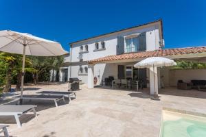 a patio with two umbrellas and a house at Villa Etoile in Cabasse