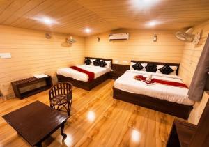 a room with two beds and a table and a chair at Hotel Royal Palace in Chittaurgarh