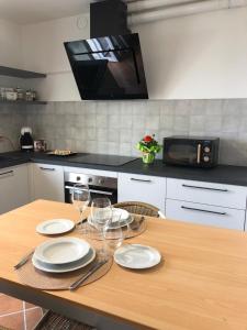a kitchen with a wooden table with plates and wine glasses at La Meridiana Apartment in Ghiffa