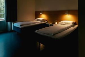 two beds in a dark room with at Falstadsenteret Hotell - Museum, minnested og senter for menneskerettigheter in Levanger +30 photos