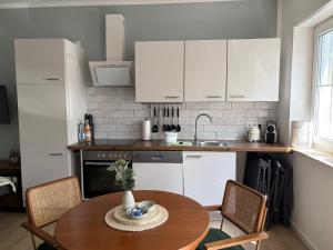 a kitchen with a wooden table and a kitchen with white cabinets at Ferienwohnung Forêt de la Sprée - Werben Spreewald in Werben +11 photos