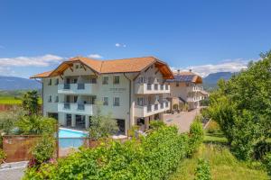an apartment building with a swimming pool and trees at Garni Hotel Peterlinhof in Caldaro