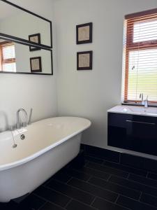 a white bath tub in a bathroom with a sink at Birch House Ballina in Ballina