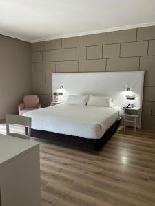 a bedroom with a large white bed and a chair at Hotel Alfonso I in Tui