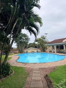 a large swimming pool in a yard with a palm tree at Aloha Sands Scottburgh in Scottburgh