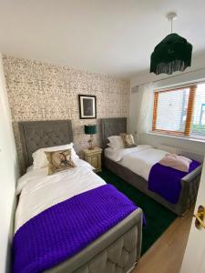 two beds in a bedroom with purple blankets at Dunboyne Apartment in Dunboyne