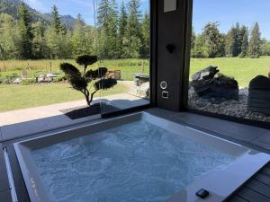 a hot tub in a room with a window at ALPENGARTEN EIGENTHAL - Private Wellness Retreat in Eigenthal