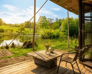 a table and chairs on a deck with a view of a lake at Krusmølle Glamping in Aabenraa