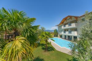 an apartment building with a swimming pool and palm trees at Garni Hotel Peterlinhof in Caldaro