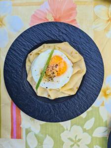 a blue plate with an egg on top of food at Gîte Mon Paradis in Vallon-Pont-dʼArc