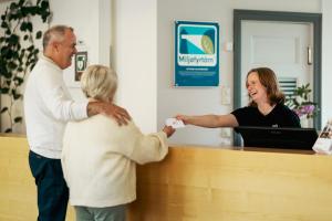 a man and a woman standing at a reception desk at Falstadsenteret Hotell - Museum, minnested og senter for menneskerettigheter in Levanger