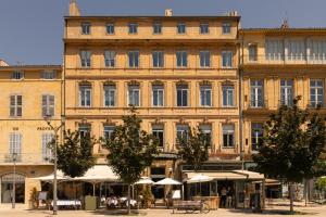 a large building with tables and umbrellas in front of it at Negrecoste Hôtel & Spa in Aix-en-Provence