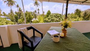 a table and chair on a balcony with a view of trees at Gypsy Walker in Varkala