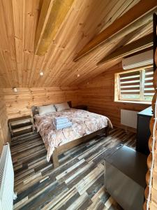 a bedroom with a bed in a wooden cabin at Міні-готель На Росі in Steblëv