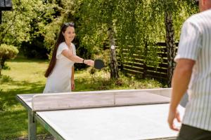 a woman playing tennis on a ping pong table at Sojka Resort in Bešeňová