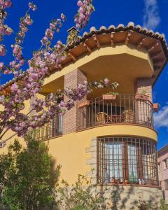 a building with a balcony and a tree with purple flowers at LA CANTERICA in Fuentes de Rubielos