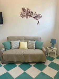 a couch in a living room with a tree on the wall at Dimora Patrizia in Scario