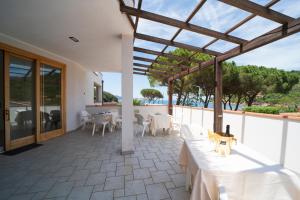 een terras met tafels en stoelen en uitzicht op de oceaan bij Hotel Punta Pina in Portoferraio