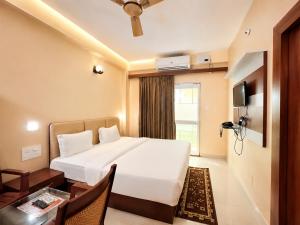 a hotel room with a large bed and a table at Hotel Golden Wave Puri - Baliapanda Housing Colony - Near Golden Beach- Parking - Restaurant in Puri