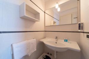 een witte badkamer met een wastafel en een spiegel bij Hotel Punta Pina in Portoferraio
