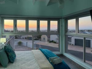 a bedroom with a bed and a large window at The Sundowner Room in Langebaan