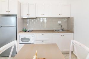 a kitchen with white cabinets and a sink and a table at Anemologio 303 Tinos in Agios Ioannis