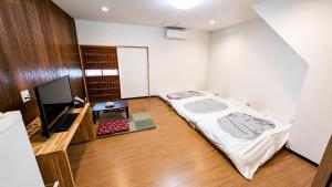 a bedroom with a bed and a flat screen tv at Takamori Guest House in Takamori +3 photos