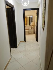 a hallway with a white tile floor and a bathroom at White Pearl Apartment in Alexandria +1 photo