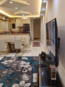 a living room with a tv and a kitchen at White Pearl Apartment in Alexandria