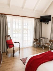 a bedroom with a bed and a chair and a table at Millard Crescent Guest House in Port Elizabeth